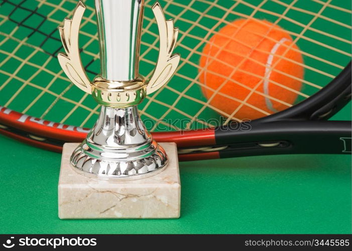 sports awards and tennis racquets on a green table