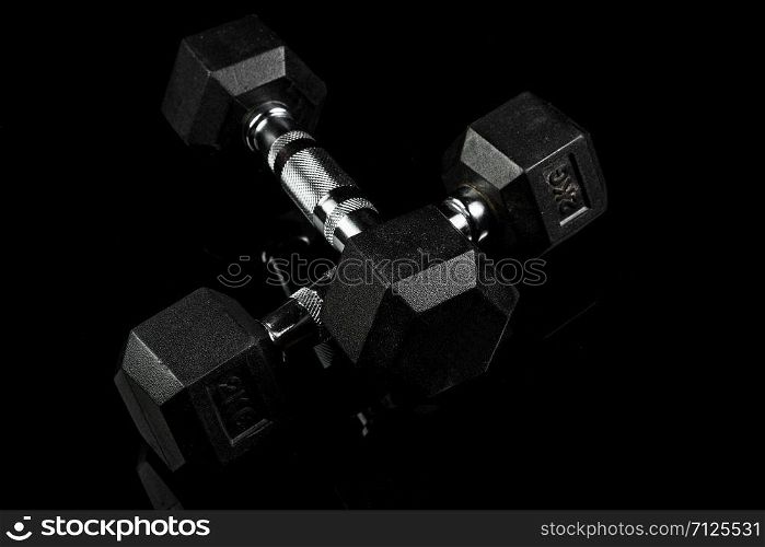 sports dumbbells with black rubber handle on black isolated background