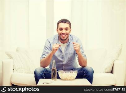 sports, happiness and people concept - smiling man watching sports on tv and supporting team at home