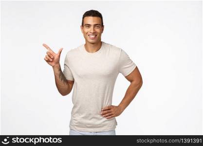 Sports, healthy people and movember concept. Handsome smiling hispanic guy in casual t-shirt, hold hand on waist relaxed, pointing left and grinning satisfied, recommend promo, advertise new product.. Sports, healthy people and movember concept. Handsome smiling hispanic guy in casual t-shirt, hold hand on waist relaxed, pointing left and grinning satisfied, recommend promo, advertise new product