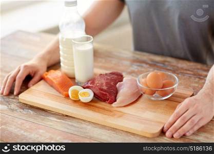sports nutrition, healthy eating and people concept - close up of male hands with food rich in protein on wooden cutting board. close up of man with food rich in protein on table