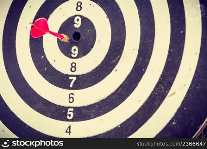 Sports, recreation concept. Red dart arrow hitting almost in the target center of dartboard. Red dart arrow hitting in the dartboard