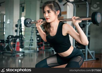 Sports woman lifting weight in fitness gym. Workout exercise and Body build up concept. Barbell lifting and Beauty theme.