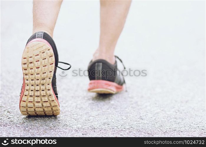Sportsman foot runner trail running outdoors. close up on shoe behind of a man running fitness jogging workout uphill in autumn trail of nature and stones. exercise healthy lifestyle and sport concept