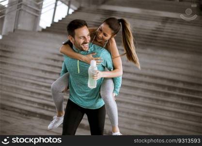 Sportsman holding a sportswoman on his back and having fun and take a rest