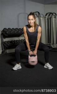 Sportswoman in gym exercising muscles