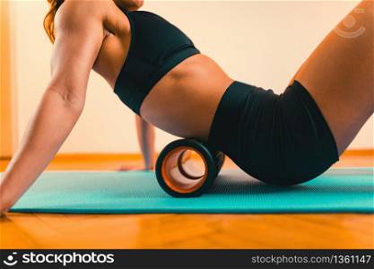 Sportswoman Massaging Lower Back with Foam Roller. Massaging Lower Back with Foam Roller