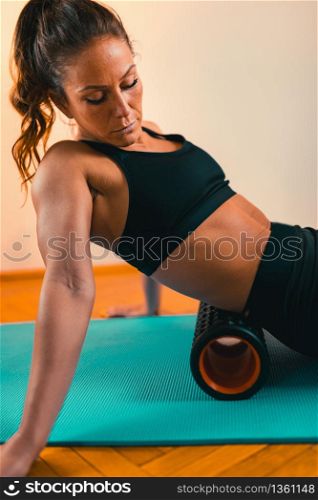 Sportswoman Massaging Lower Back with Foam Roller. Massaging Lower Back with Foam Roller