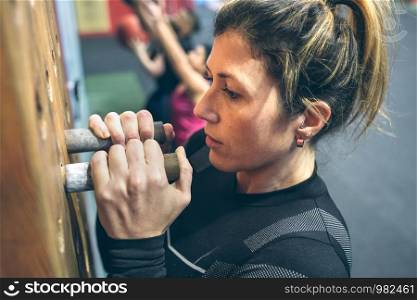Sportswoman training hanging on the pegboard at the gym. Woman hanging on the pegboard