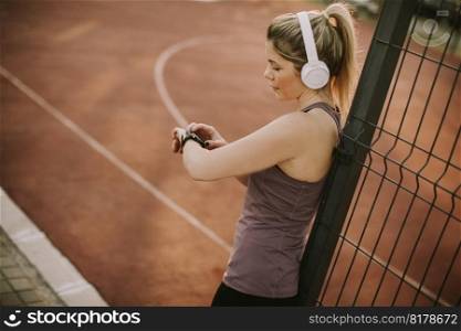 Sportwoman checking pulse on fitness smart watch device at outdoor