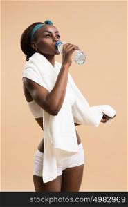 Sporty african woman drinking water from bottle. Fit sexy body