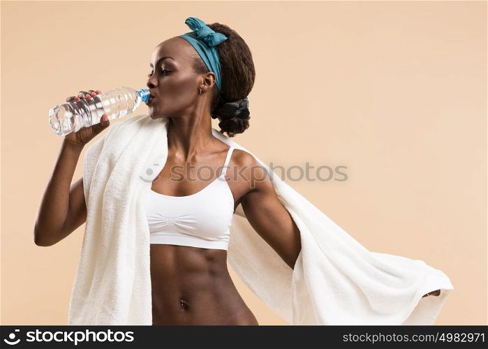 Sporty african woman drinking water from bottle. Fit sexy body