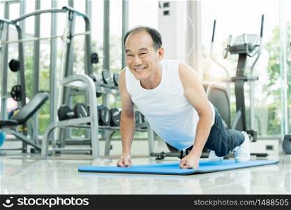 Sporty Asian Senior man in white shirt push up while exercising at the gym. Happy smiling Healthy Old male stretching after a workout. Sport, Recreation, Good health.