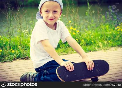 Sporty child with his skateboard outdoor. Active boy skateboarding on pavement sidewalk. Kid practicing outside. . Sporty child kid with his skateboard outdoor.