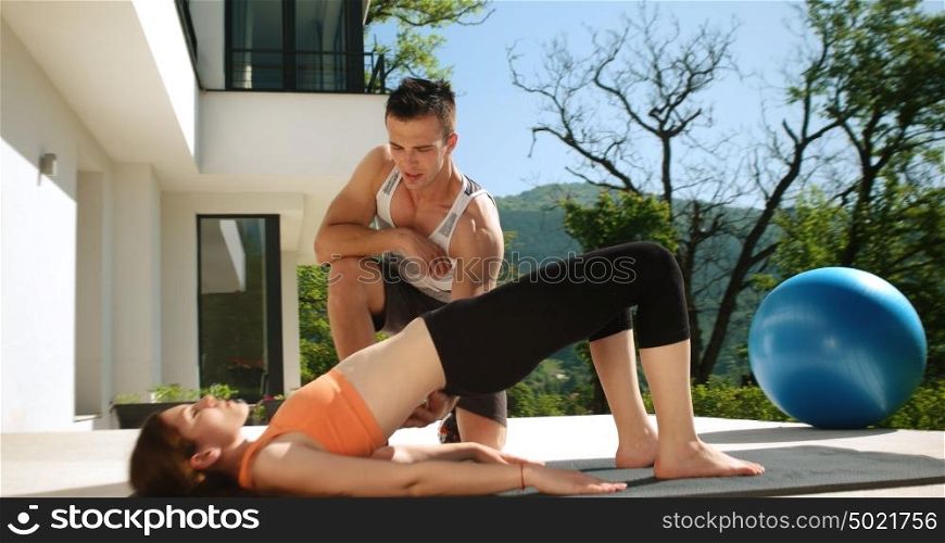 sporty couple exercising together on terace in front of mansion