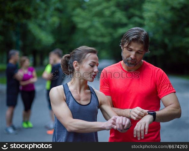 sporty couple using smart watches. Young sporty couple using smart watches starting their timer before jogging