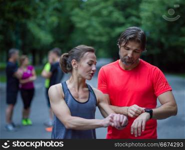 sporty couple using smart watches. Young sporty couple using smart watches starting their timer before jogging