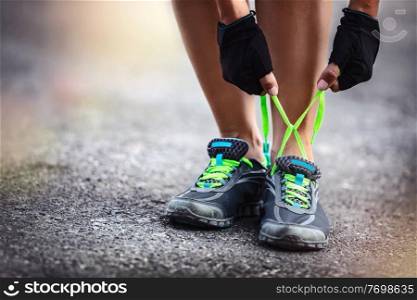 Sporty female runs outdoor, photo of a sportswoman crouched to tie shoelaces, workout, happy healthy lifestyle, summer activity