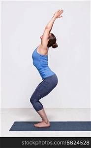 Sporty fit woman doing Surya Namaskar ashtanga vinyasa yoga asana Utkatasana - chair pose. Woman doing ashtanga vinyasa yoga asana Utkatasana