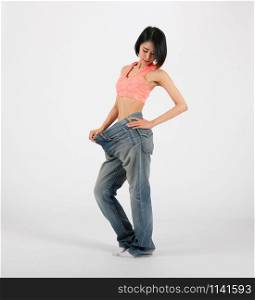 sporty fitness woman in loose jeans after losing weight on white background. healthy sport lifestyle
