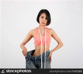 sporty fitness woman in loose jeans after losing weight on white background. healthy sport lifestyle