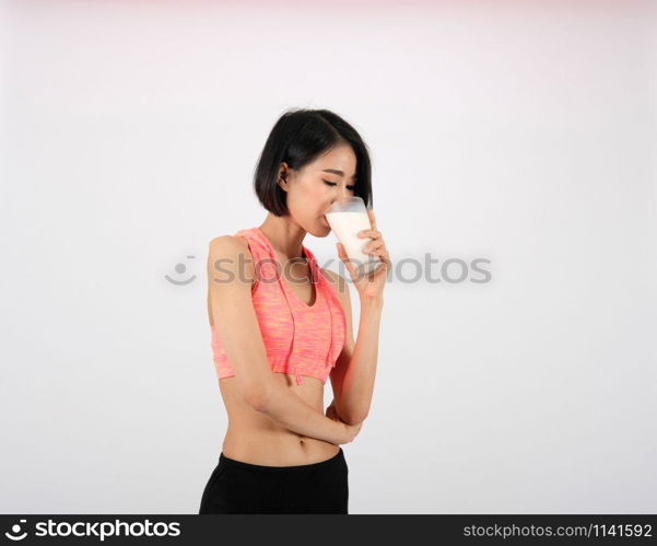 sporty fitness woman in sportswear drinking milk on white background. healthy sport lifestyle