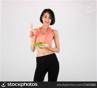 sporty fitness woman in sportswear with vegetable salad bowl on white background. healthy sport lifestyle