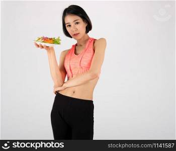 sporty fitness woman in sportswear with vegetable salad bowl on white background. healthy sport lifestyle