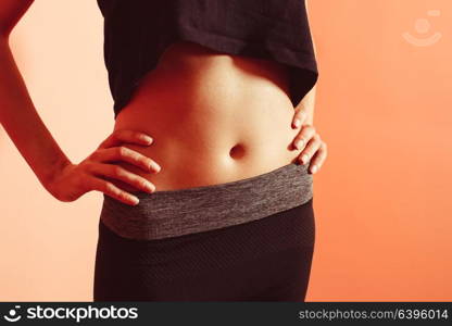 Sporty girl in dark sportswear demonstrating press stomach. The girl with a sports body