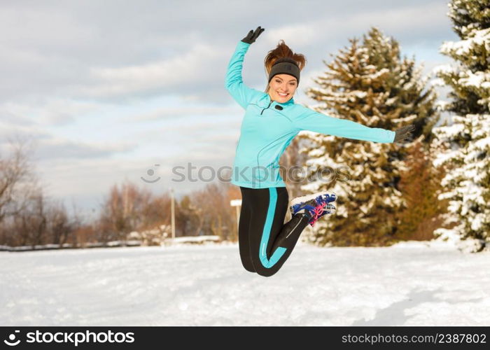 Sporty girl jumping in snow with trees in background. Winter sports, outdoor fitness, nature workout, health concept.. Winter sport, girl jumping in snow