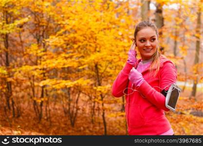Sporty girl rest in forest listening music.. Rest and relax. Young attractive sporty girl with mobile phone smartphone on her arm with headphones listening music.