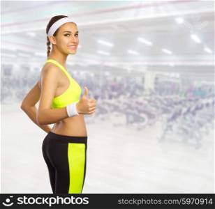 Sporty girl shows ok gesture in fitness club