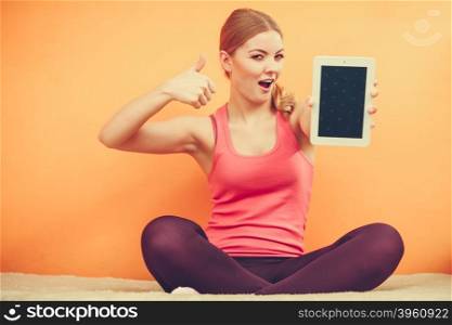 Sporty girl with pc tablet. Blank screen copyspace. Sporty fitness girl holding tablet computer with blank screen showing copyspace. Happy smiling woman advertising new modern technology giving thumb up gesture.
