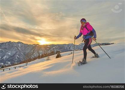 Sporty girl with snowshoes in sunset landscape