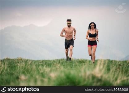 Sporty man and woman run hot in the summer on hill meadows