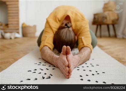 Sporty man meditating alone at home apartment. Peaceful calm hipster guy practicing yoga indoors holding hands together. Sporty man meditating alone at home apartment