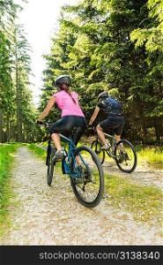 Sporty mountain bikers in forest from behind