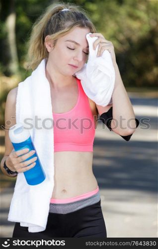sporty smiling blonde standing with towel on a sunny day