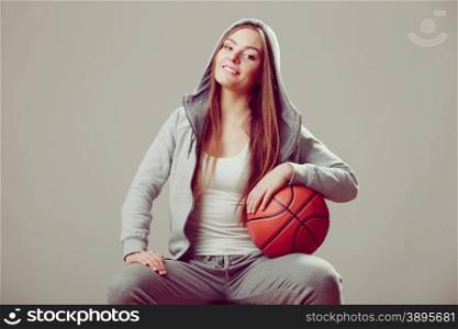 Sporty teen girl in hood holding basketball. . Sporty teenager girl wearing hooded sweatshirt holding basketball. Teen sport.