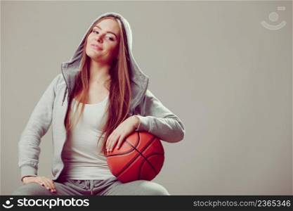 Sporty teenager girl wearing hooded sweatshirt holding basketball. Teen sport. . Sporty teen girl in hood holding basketball.