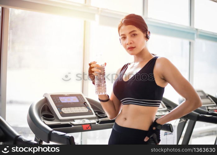 Sporty woman asia drinking water after exercises in the gym. Fitness - concept of healthy