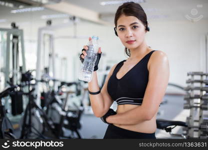 Sporty woman asia drinking water after exercises in the gym. Fitness - concept of healthy