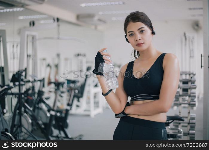 Sporty woman asia drinking water after exercises in the gym. Fitness - concept of healthy