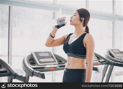 Sporty woman asia drinking water after exercises in the gym. Fitness - concept of healthy
