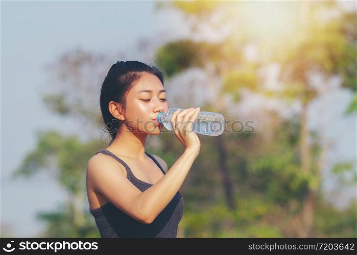 Sporty woman asian drinking water outdoor on sunny day