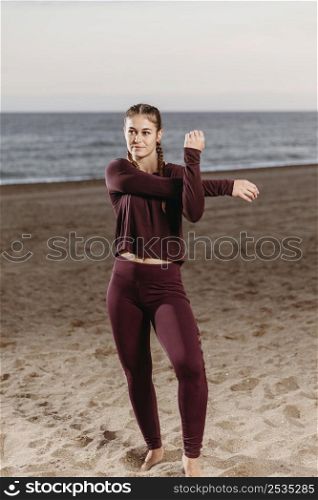 sporty woman by beach stretching