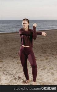 sporty woman by beach stretching