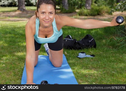 sporty woman doing plank exercise with dumbbells