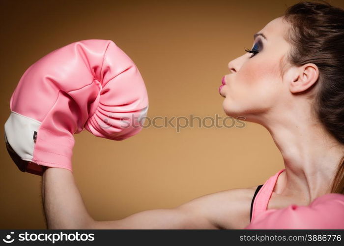 Sporty woman female boxer model wearing big fun pink gloves playing sports boxing studio shot, brown background