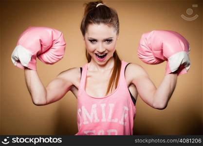 Sporty woman female boxer model wearing big fun pink gloves playing sports boxing studio shot, brown background